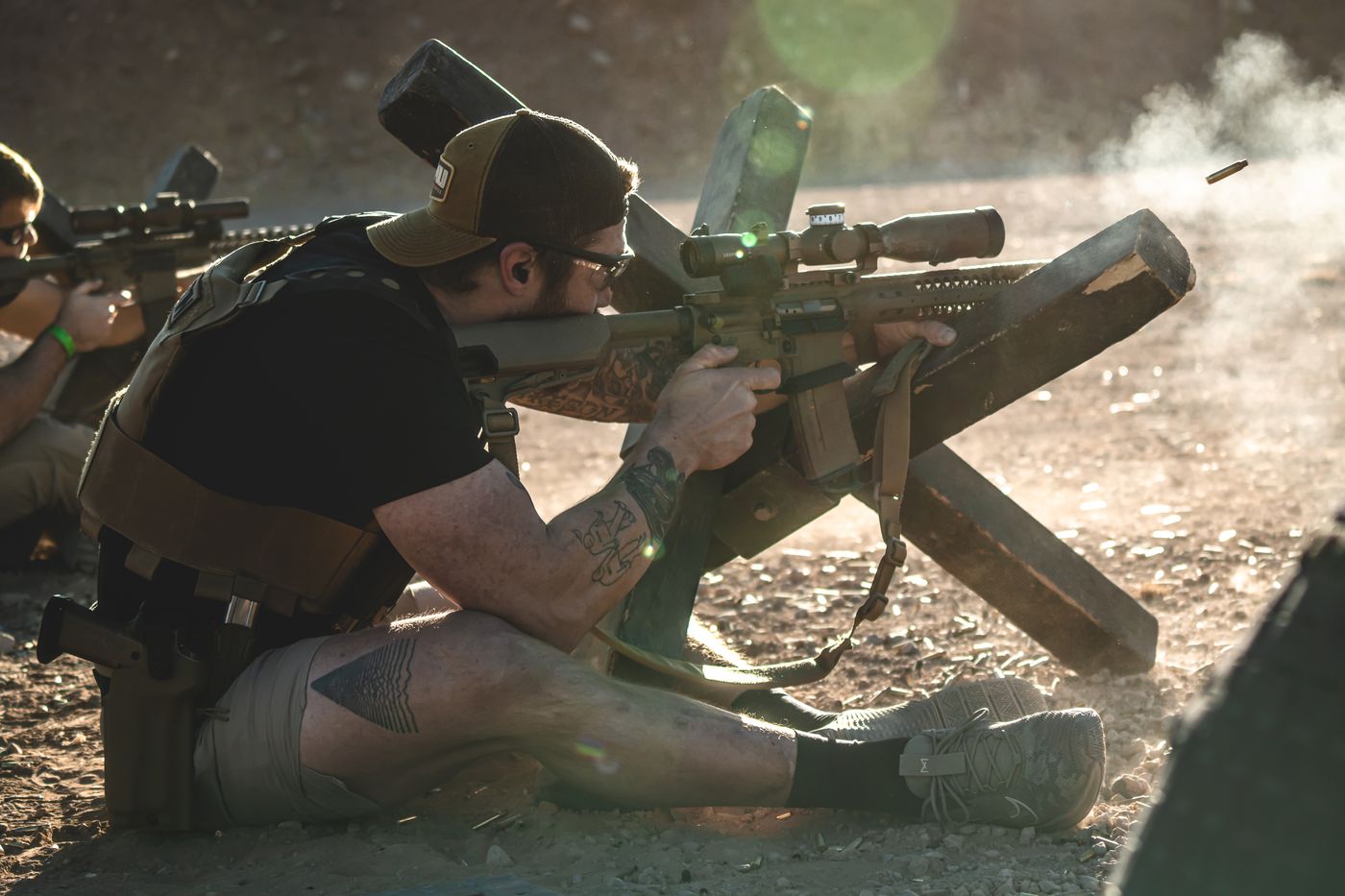 A competitor firing a rifle seated at a wooden barricade